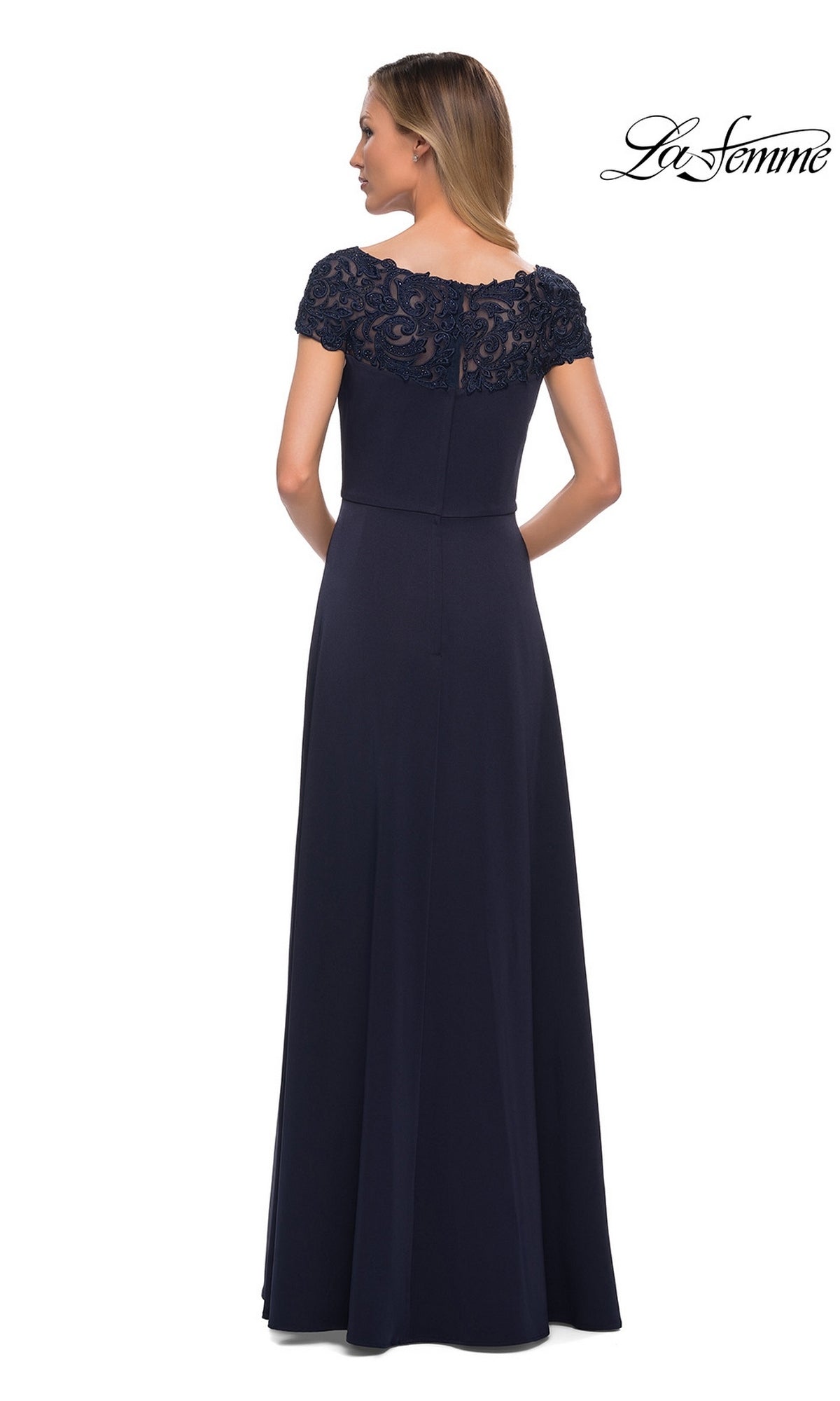 Woman facing away in a floor-length navy Long Formal Dress: La Femme 29511 with lace bateau neckline and cap sleeves, against a plain white background. “La Femme” logo top right.